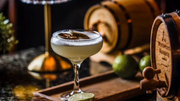 A foamy cocktail in a coupe glass on a wooden tray at The Hercules Pillars, Holborn