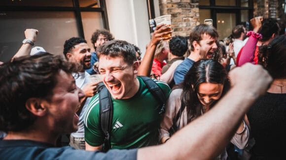 A crowd of people celebrating outside St Christopher's Pub on Borough High Street, London Bridge