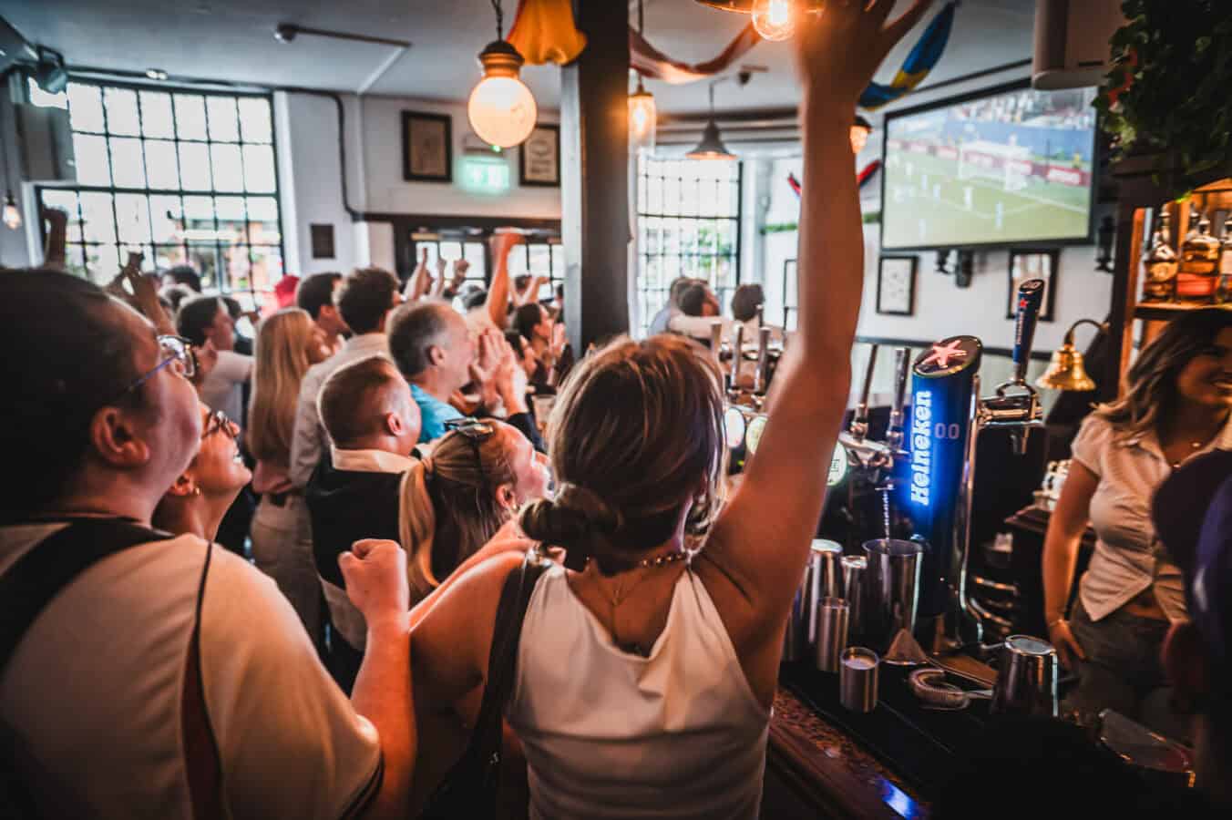 Fans seated watching live football on a large projector screen inside St Christopher's Pub, Borough High Street, London Bridge