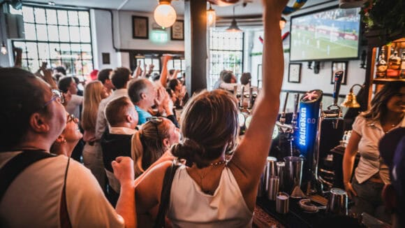 Fans seated watching live football on a large projector screen inside St Christopher's Pub, Borough High Street, London Bridge