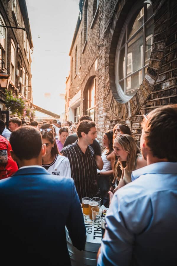 A crowd of people drinking in the sunlit alley outside St Christopher's Pub on Borough High Street, London Bridge