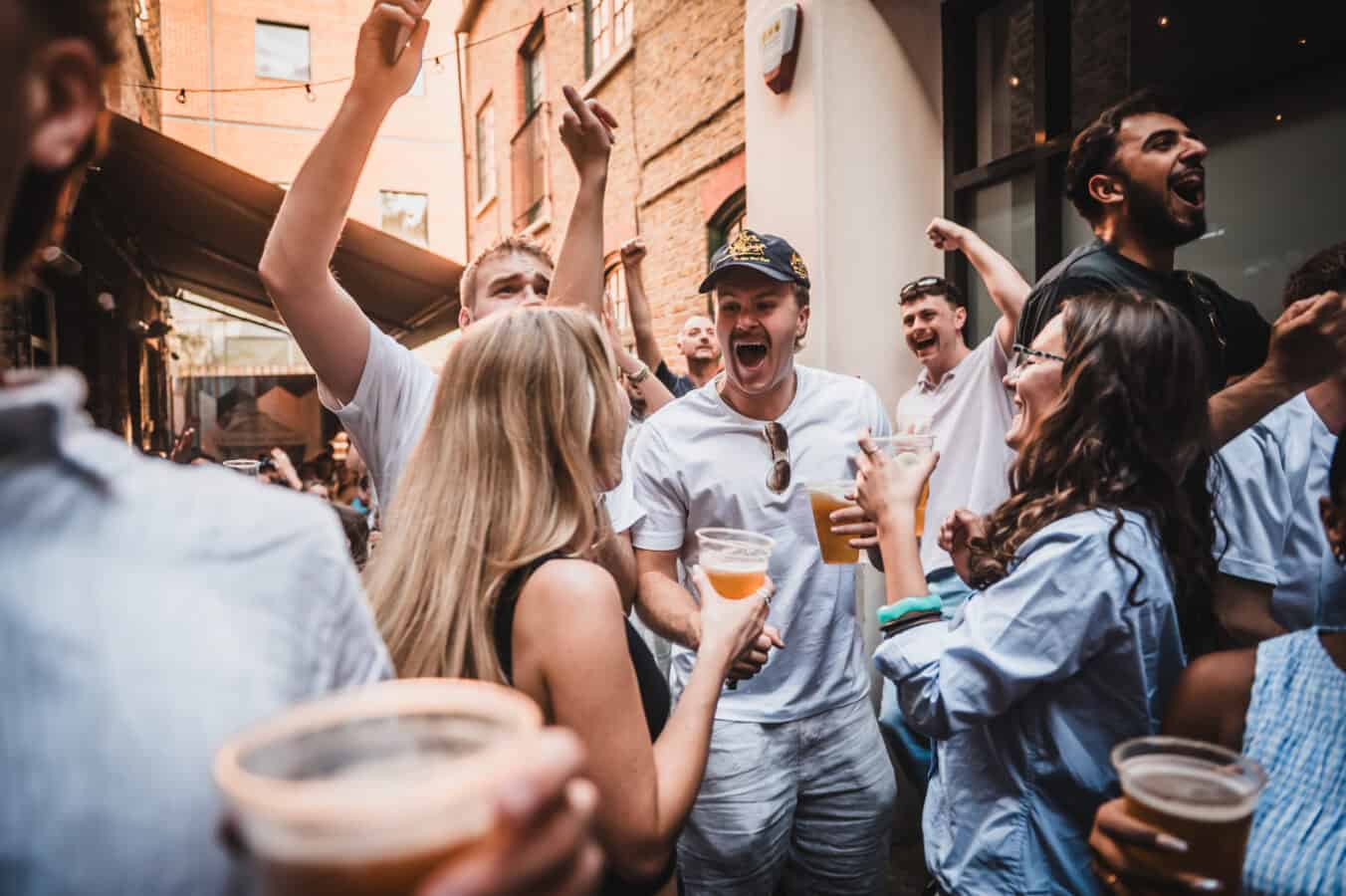 A crowd of people celebrating outside St Christopher's Pub on Borough High Street, London Bridge