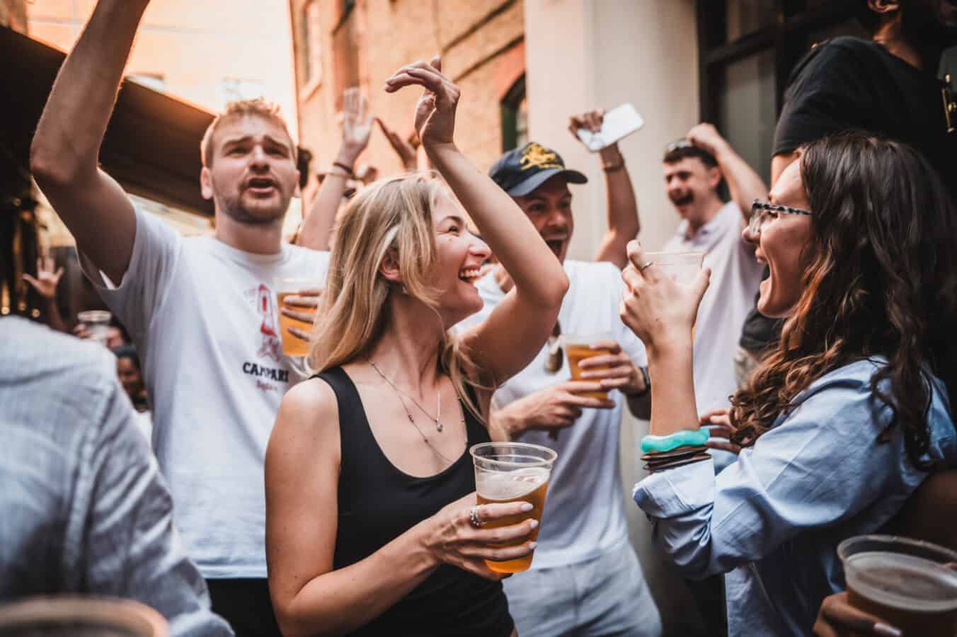 A group of friends celebrating with drinks outside St Christopher's Pub on Borough High Street on a summer evening